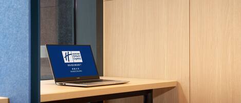 Una laptop sobre una mesa de madera con un cartel que indica un centro de internet.