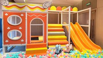 A children's play area with a slide, climbing steps, and a ball pit.