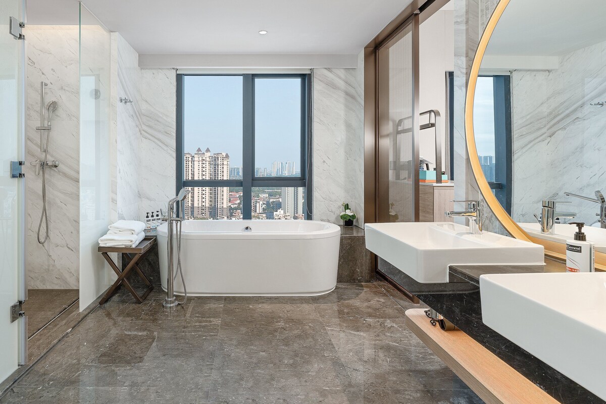 Un baño moderno con una bañera grande, dos lavamanos y un espejo amplio.