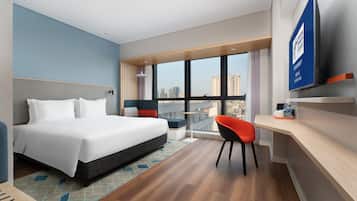 Quarto de hotel moderno com uma cama grande, uma escrivaninha, uma cadeira e uma televisão.