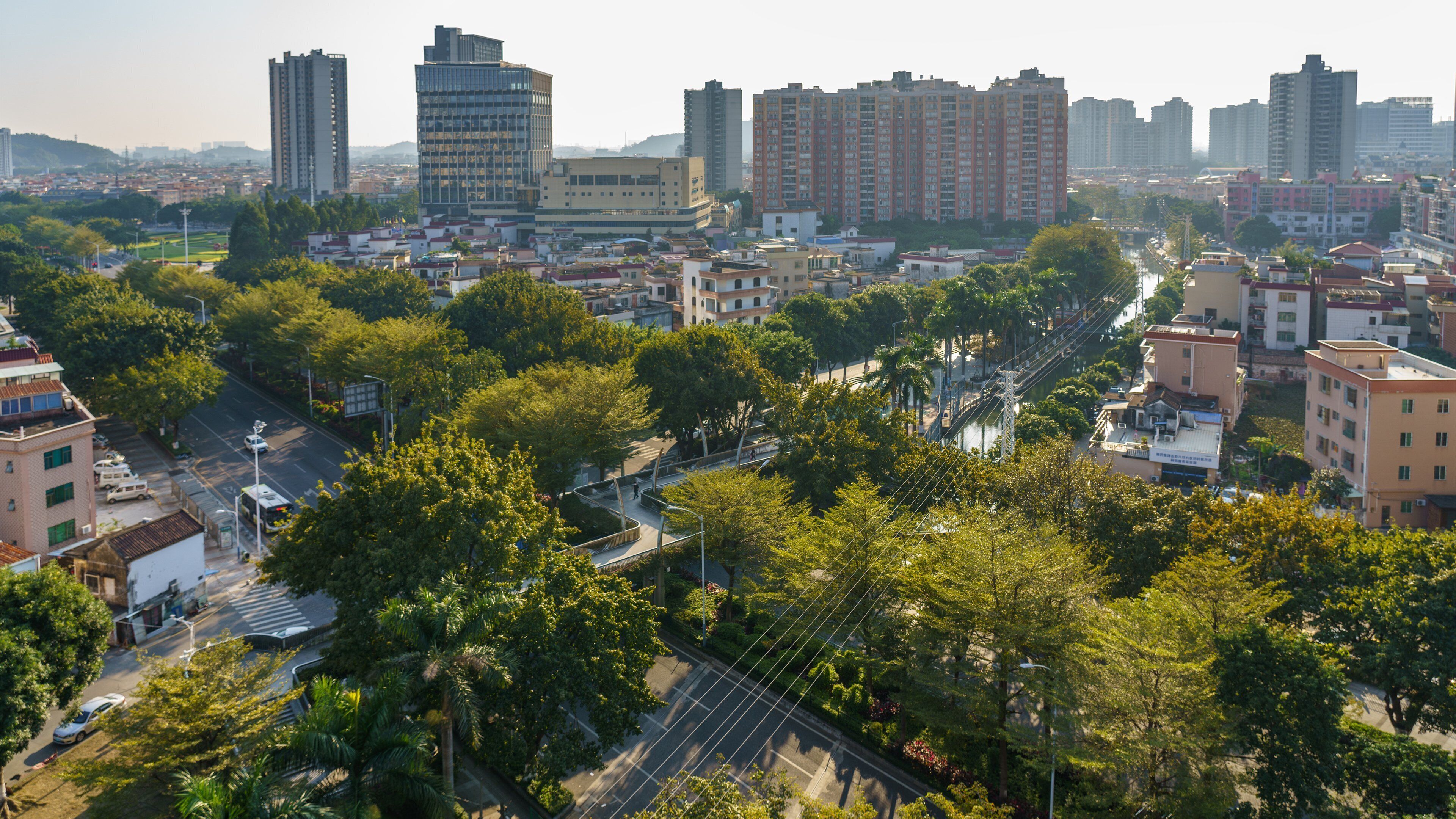 A cityscape with high-rise buildings, a river, and a park with trees.