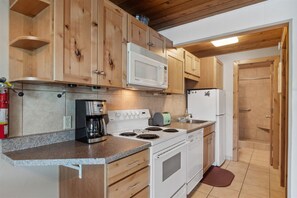 Kitchen area with stove, coffee maker, microwave, and sink.