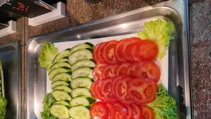 Ein Buffetschälchen mit Gurkenscheiben, Tomaten und Salat.