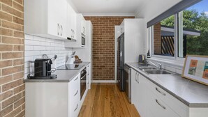 Una cocina moderna con armarios blancos, pared de ladrillo y una ventana.