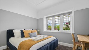 Un dormitorio con cama, ventana con vistas, una mesa de madera y una silla.