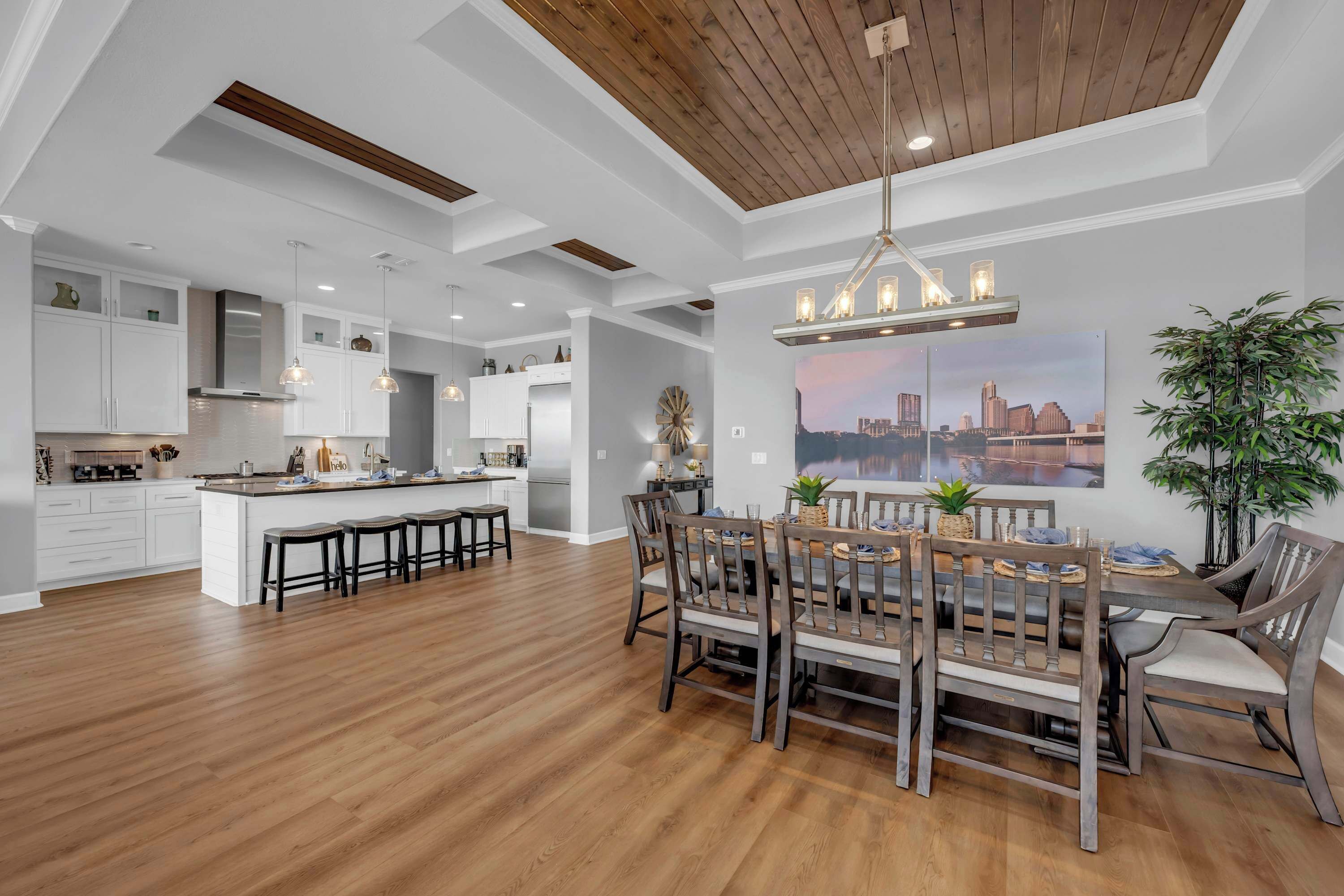 Una cocina amplia con una isla central, piso de madera y un comedor con una mesa grande y sillas.