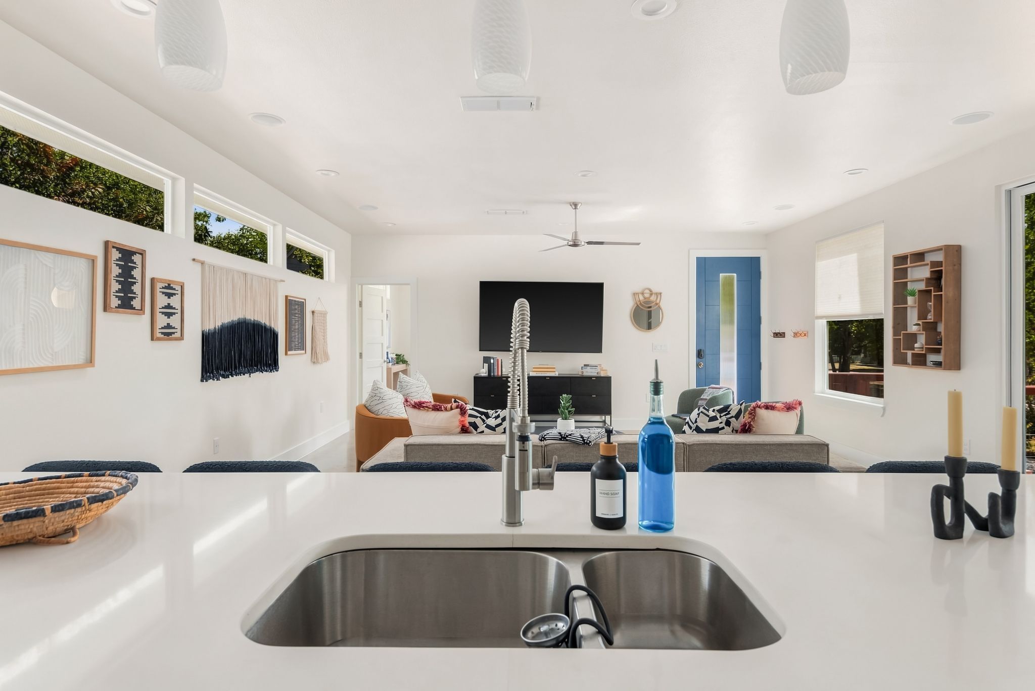 A modern kitchen with a central island, stainless steel sink, and a ceiling fan.