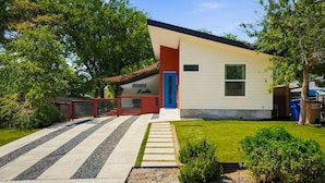 A single-story house with a red door, a small front yard, and a pathway leading to the entrance.