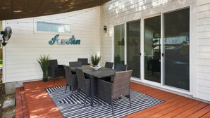 An outdoor patio with a dining table and chairs, a potted plant, and a 'Austin' sign on the wall.