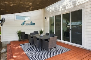 Un patio exterior con una mesa de comedor y sillas, una planta en maceta y un letrero que dice 'Austin' en la pared.