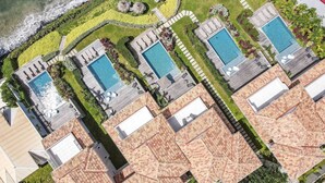Vista aérea de um resort com várias piscinas, uma praia e jardins bem cuidados.