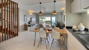 Uma cozinha moderna com área de refeições, com luminárias pendentes, escada de madeira e vista para o exterior.