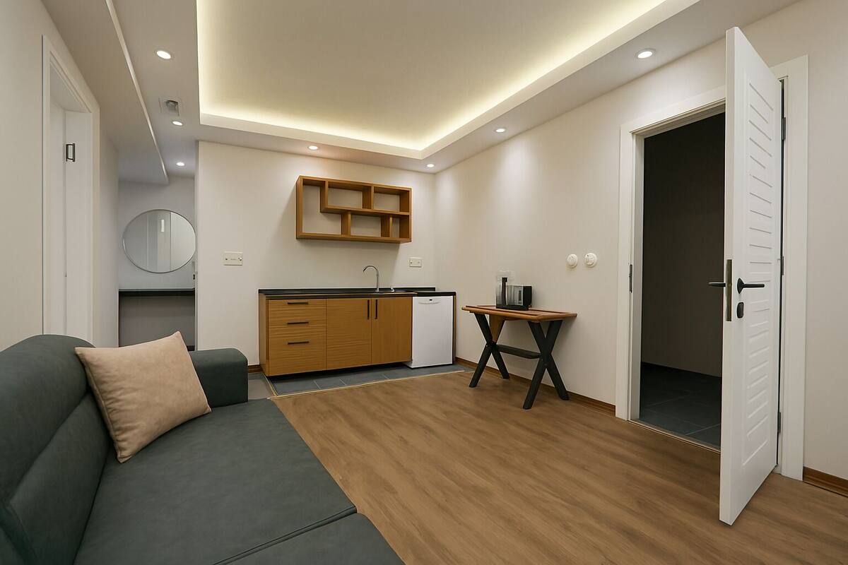 A modern, compact living space with a kitchenette, a dining table, and a sofa.