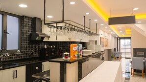 Una cocina moderna con armarios blancos y negros, una isla central con un lavamanos y una estantería para copas sobre la isla.