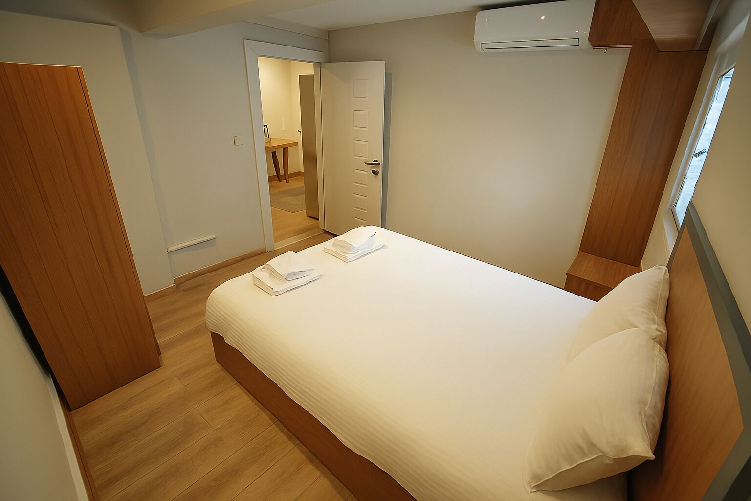 Une chambre d’hôtel moderne avec un lit bien fait, un plancher en bois et une porte donnant sur une salle de bain.