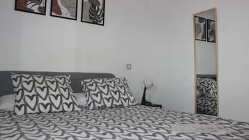 Un dormitorio con una cama, almohadas estampadas con motivos de corazón, una lámpara de noche y arte abstracto en la pared.