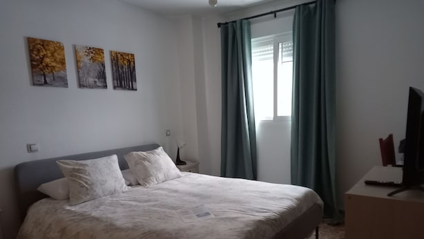 A bedroom with a bed, a nightstand, a lamp, and a television. There are three paintings on the wall. - Casa de Huéspedes Villa de las Hortensias (Bustarviejo)