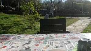 A table set outdoors with a tablecloth featuring various illustrations, a bowl of strawberries and raspberries, a mug, and a plate with food remnants. - Casa de Huéspedes Villa de las Hortensias (Bustarviejo)