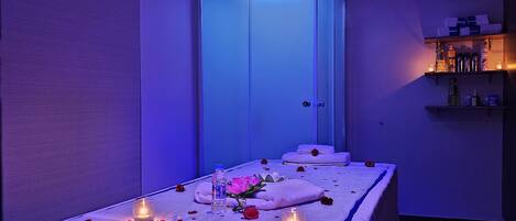 A room with a massage table, candles, and a bouquet of flowers.