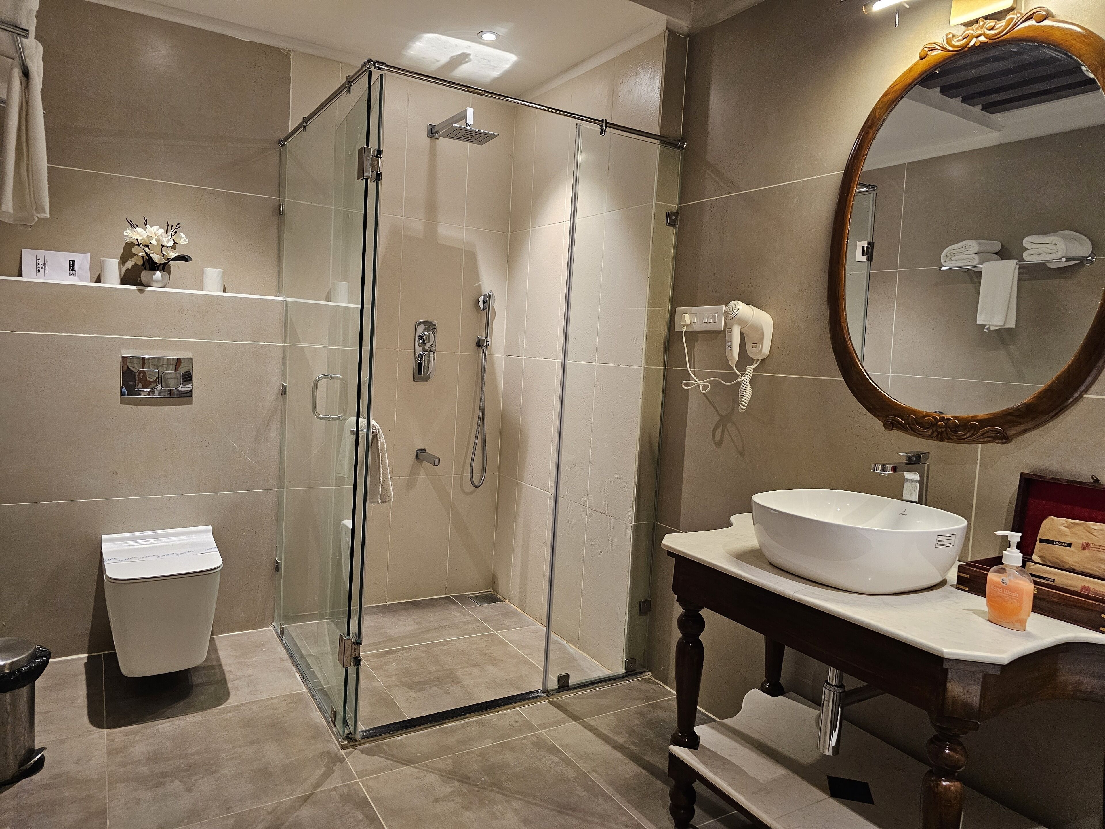 Ein modernes Badezimmer mit einer Glaskabine zur Dusche, einem weißen Waschbecken und einem großen Spiegel.