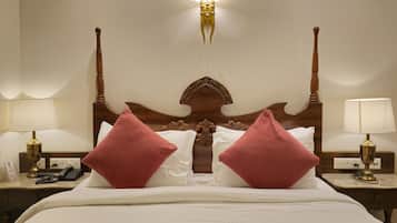 Habitación de hotel con una cama grande, dos mesitas de noche, una lámpara de pared y un cabecero decorativo.
