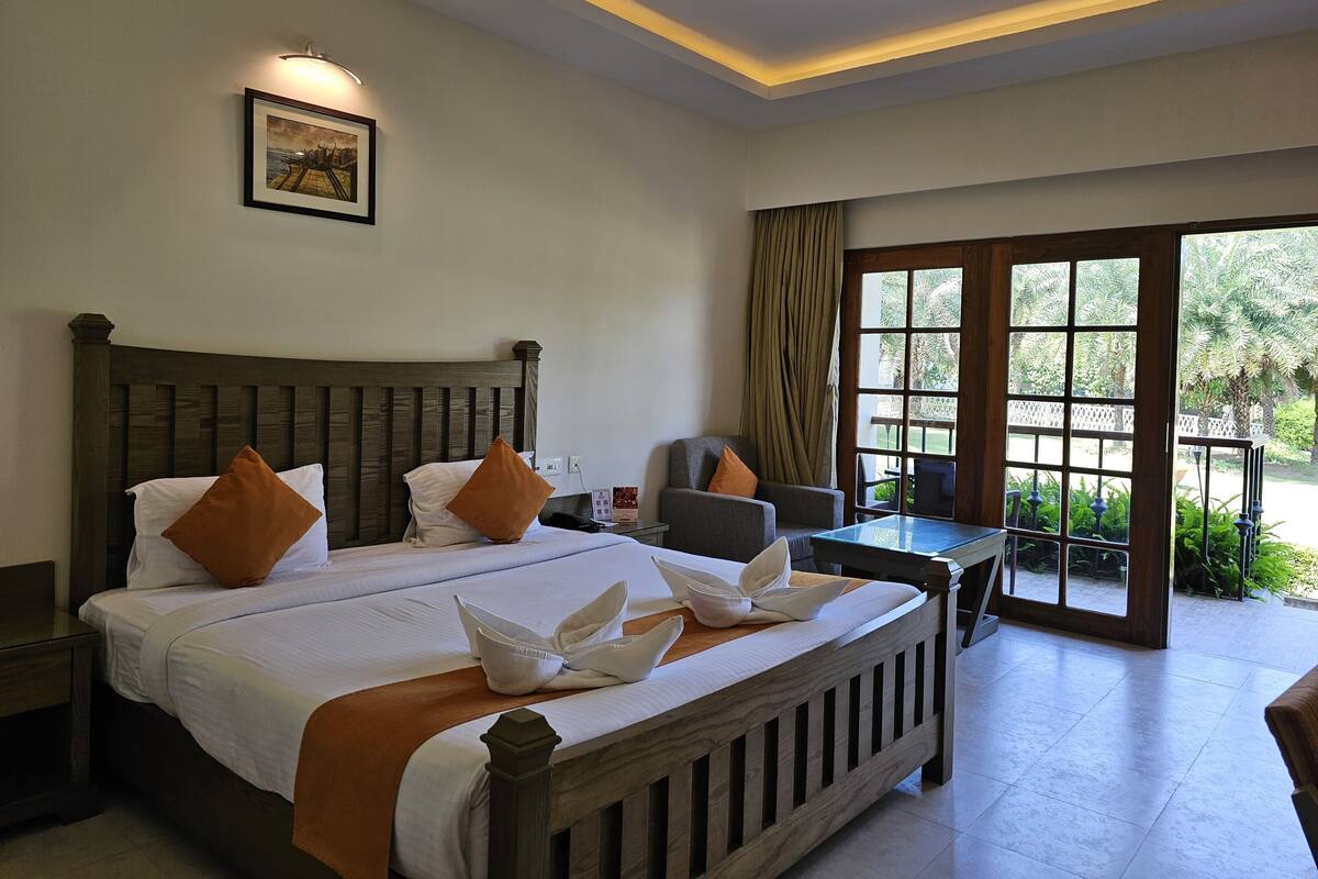 A hotel room with a large bed, a desk, and a view of the outdoors.
