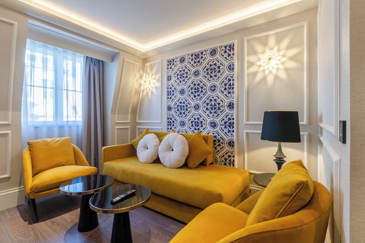 Una sala de estar moderna con un sofá amarillo, dos sillones, una mesa de centro y una pared con estampado.