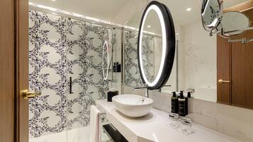 A modern bathroom with a white sink, a large mirror, and a shower area.