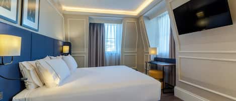 A hotel room with a large bed, bedside tables, a flat-screen TV, and framed pictures on the wall.