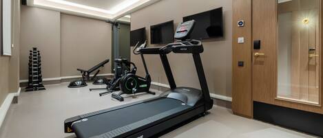 Une salle de sport moderne pour la maison, équipée d’un tapis de course, d’un vélo d’appartement et d’un banc de musculation.