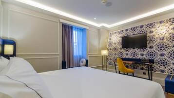 Una camera d'albergo con un letto grande, una scrivania con una sedia, una TV a schermo piatto fissata al muro e un rivestimento murale con motivi a mosaico.
