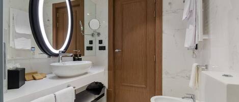 Un baño moderno con un espejo grande, dos lavamanos, una bañera y una puerta de madera.