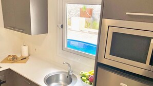 A modern kitchen with a stainless steel sink, a microwave, and a window overlooking a pool. - Luxury villa Masca with private heated pool (Costa Adeje)