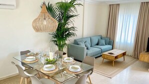 A modern living room with a glass dining table set for four, a grey sofa, a coffee table, and a large potted plant. - Luxury villa Masca with private heated pool (Costa Adeje)