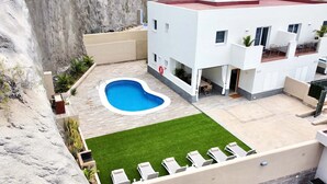 A modern building with a swimming pool, a grassy area, and lounge chairs. - Luxury villa Masca with private heated pool (Costa Adeje)