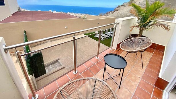 A balcony with a view of the ocean, two wicker chairs, and a small table. - Luxury villa Masca with private heated pool (Costa Adeje)