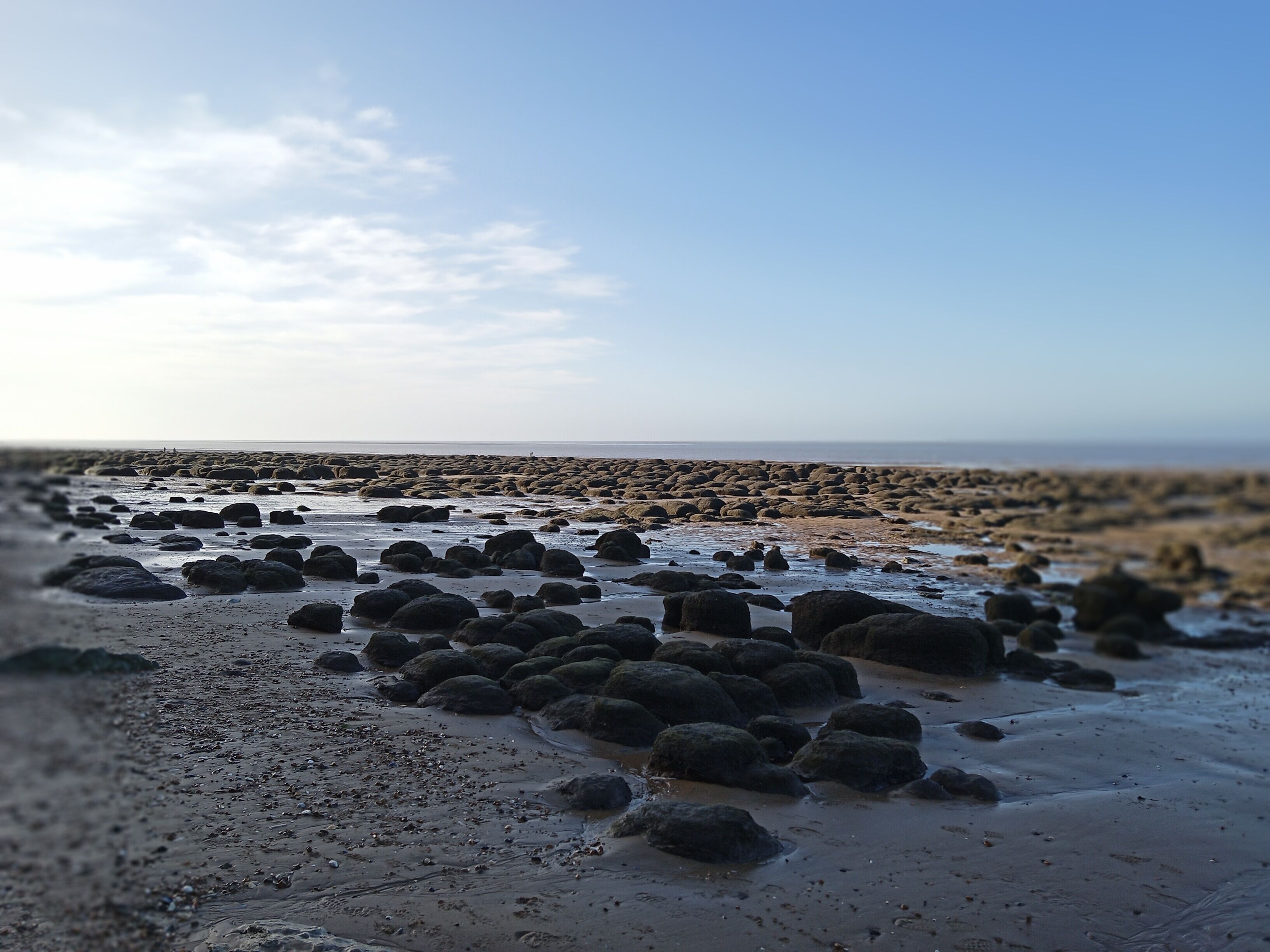 A beach with large rocks and a clear sky.