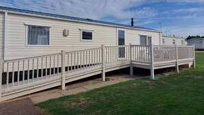 Une rangée de maisons mobiles avec une allée couverte et une pelouse devant.