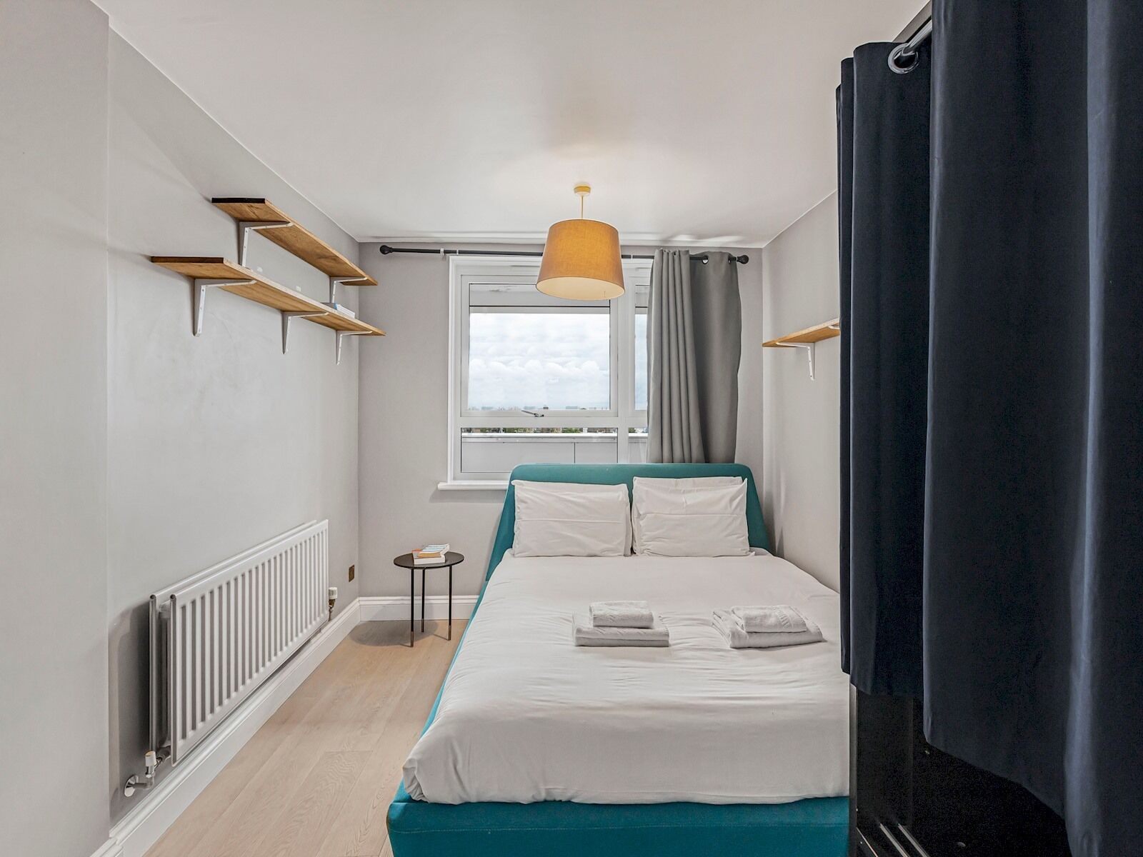 Une chambre à coucher avec un lit, une fenêtre, un radiateur et un luminaire suspendu.