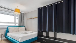 A modern hotel room with a bed, a bedside table, a lamp, a window with curtains, and a wardrobe. - Modern 1 bedroom Apartment with views on West London - Pass the Keys (London)