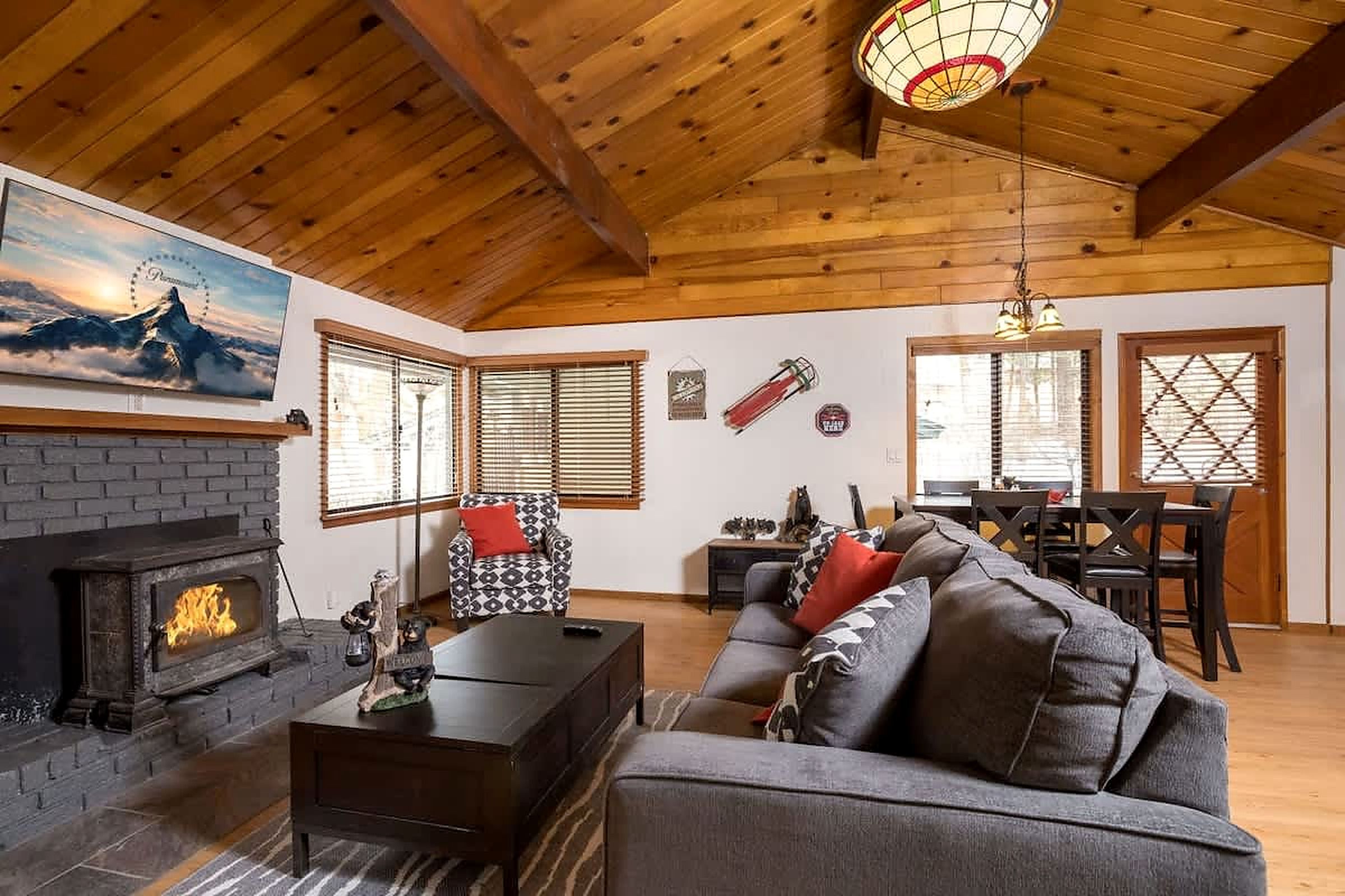 A cozy living room with a fireplace, a sofa, and a dining area with a chandelier.