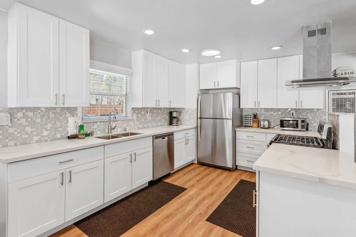 A modern kitchen with white cabinets, a stainless steel refrigerator, a microwave, and a dishwasher.