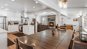 A spacious kitchen with white cabinetry, a large dining table, and a fireplace. - Modern and Clean with a Spa! Close to Snow Summit. (Big Bear)