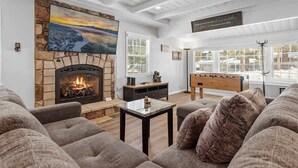 A cozy living room with a stone fireplace, a large painting, and a foosball table. - Modern and Clean with a Spa! Close to Snow Summit. (Big Bear)
