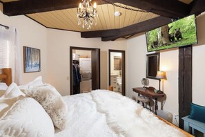 Un dormitorio con una cama grande, un escritorio, una silla, un televisor y un cuadro con osos.