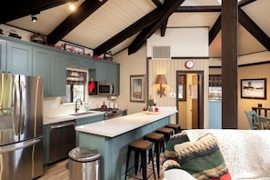 Una cocina con una isla central, taburetes de bar y un comedor con mesa y sillas.