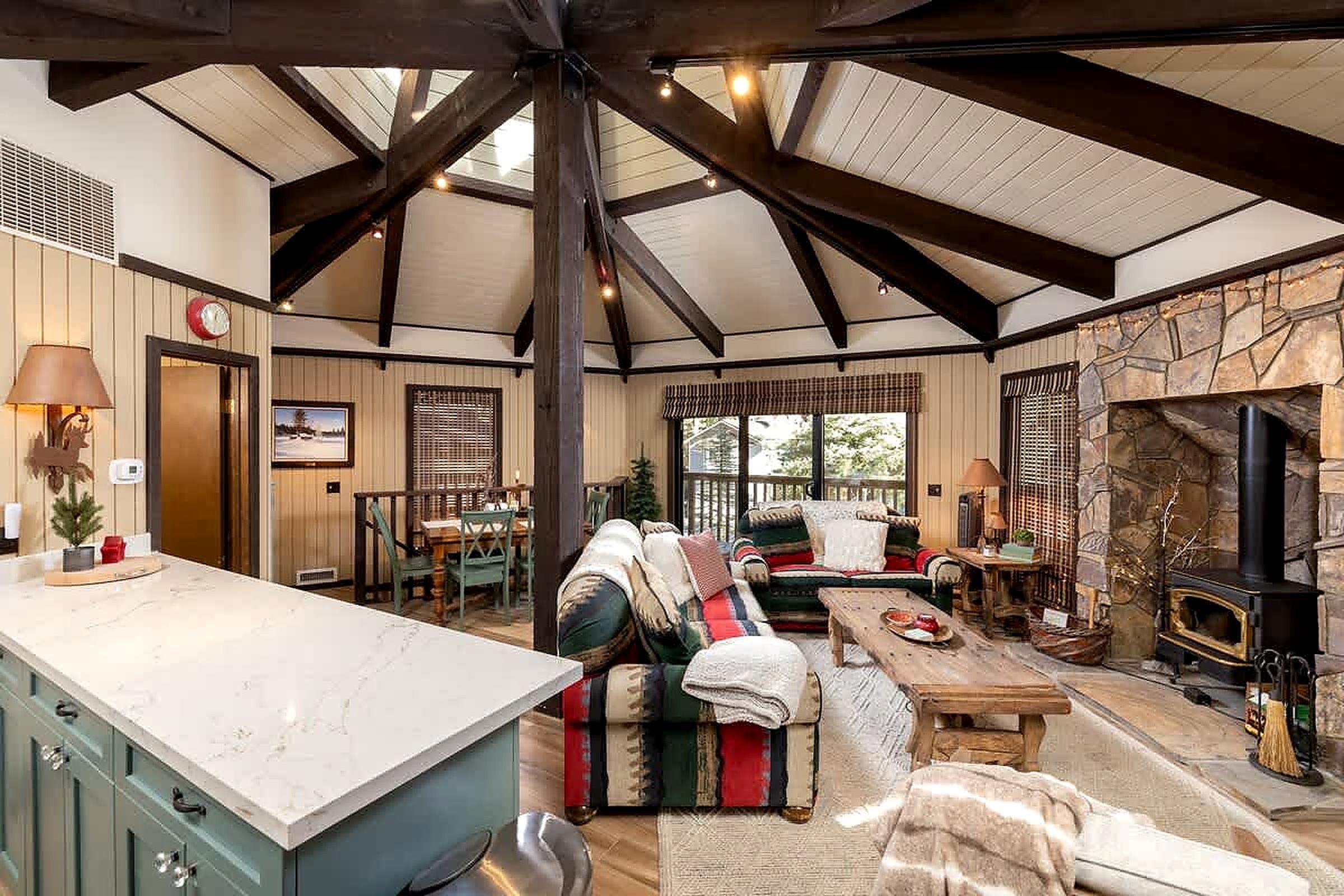 A spacious living area with a stone fireplace, a large sofa, and a dining table.