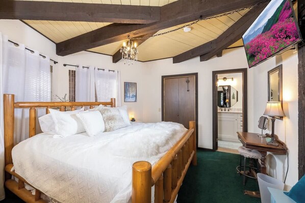 Un dormitorio con cama de madera, un escritorio, una silla, un espejo y una araña.