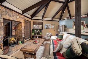 Una sala de estar acogedora con chimenea de piedra, un televisor y una mesa de centro de madera.