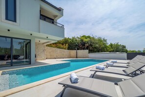 A modern pool area with lounge chairs and a clear blue pool.